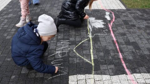Na zdjęciu dzieci rysujące kolorową kredą po chodniku