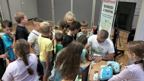 Na zdjęciu Paweł Gołuch podpisujący książki dzieciom, uczestniczącym w spotkaniu