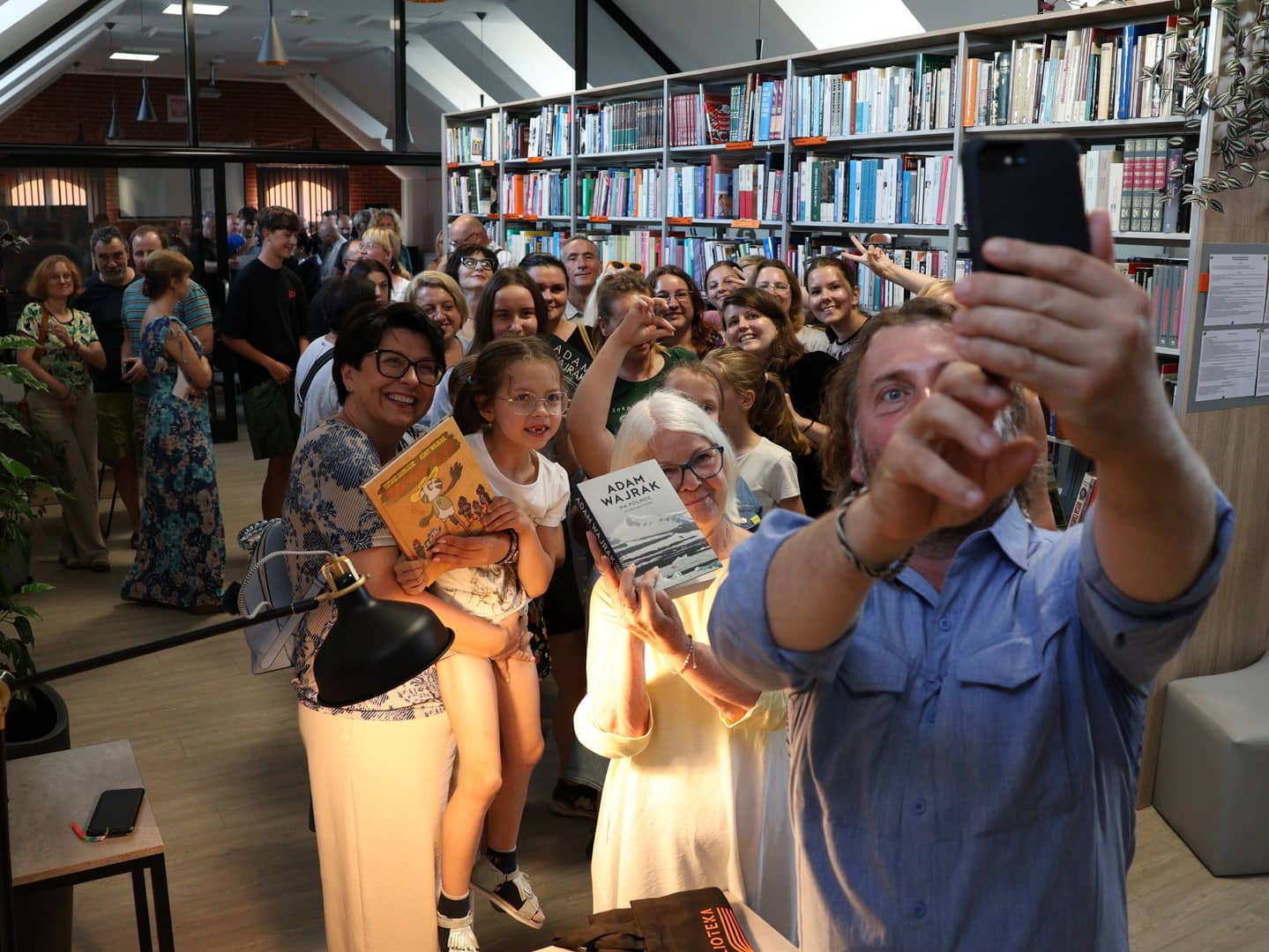 Na zdjęciu Adam Wajrak robiący selfie z uczestnikami spotkania